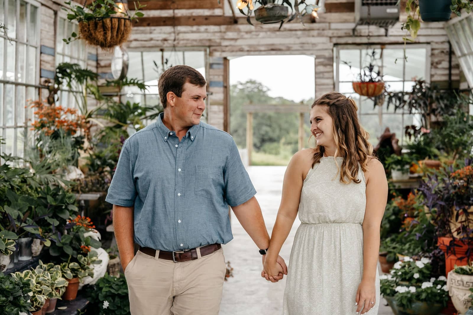 Engaged couple walking hand in hand through a garden setting during a Georgia engagement photography session.