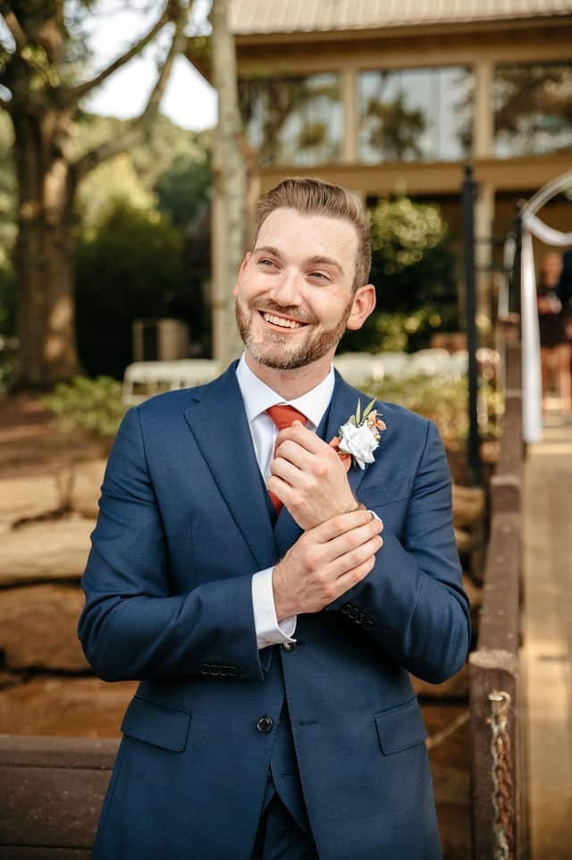 Groom smiling in his suit and boutonniere during a wedding portrait session with a wedding photographer in Georgia.