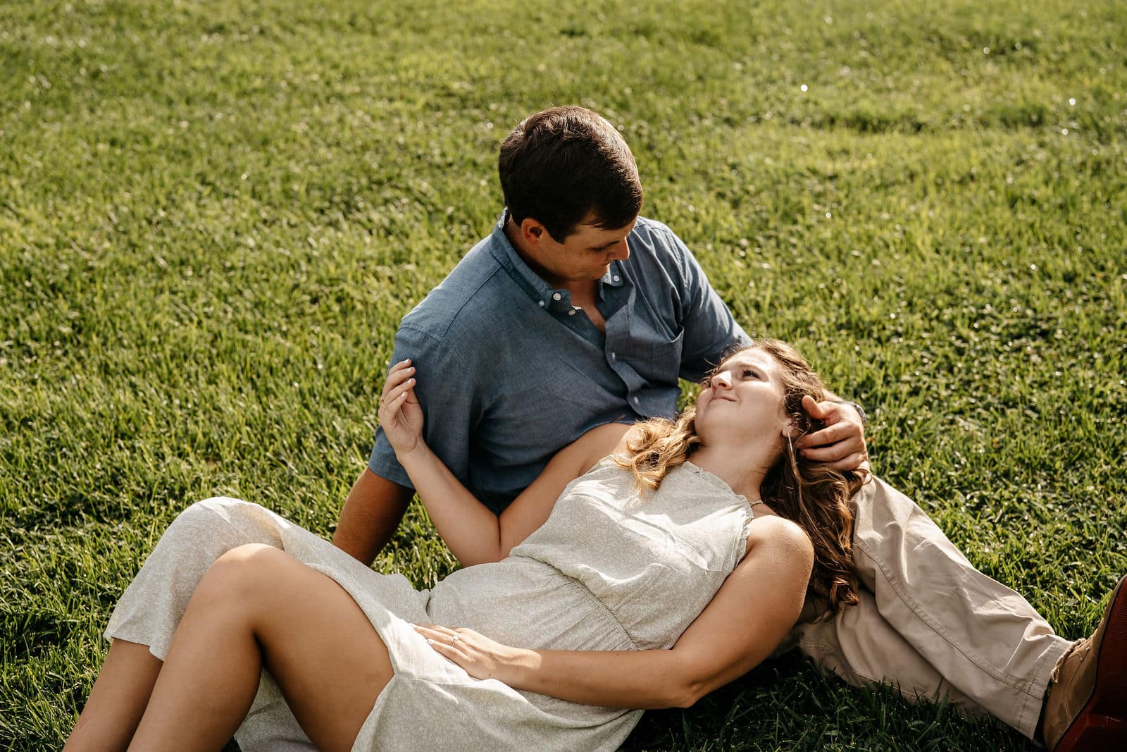 Engaged couple sharing a relaxed moment together on the grass captured by a Georgia wedding videographer.