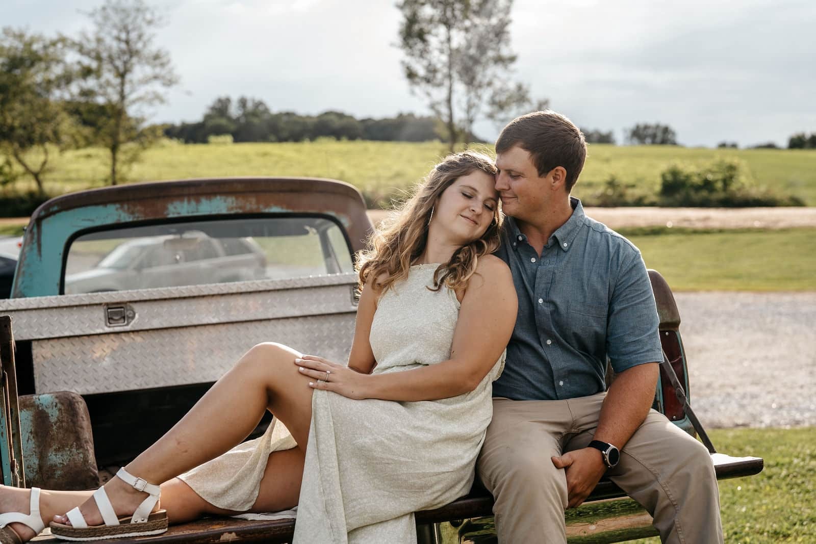 Engaged couple relaxing together beside a vintage truck during a Georgia engagement session photographed by a Georgia wedding photographer.