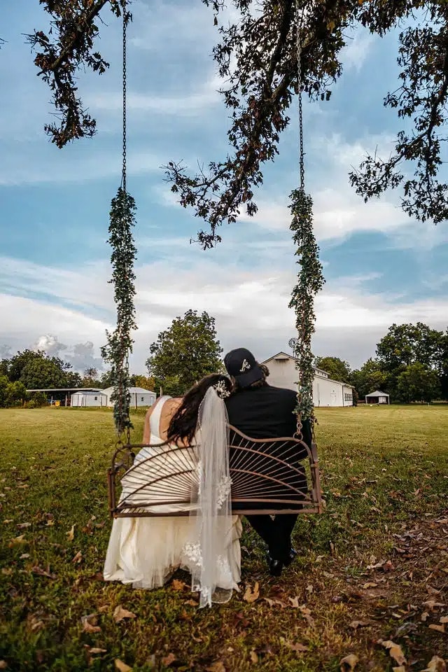 Bride and groom sitting together on an outdoor swing during their Georgia wedding celebration.