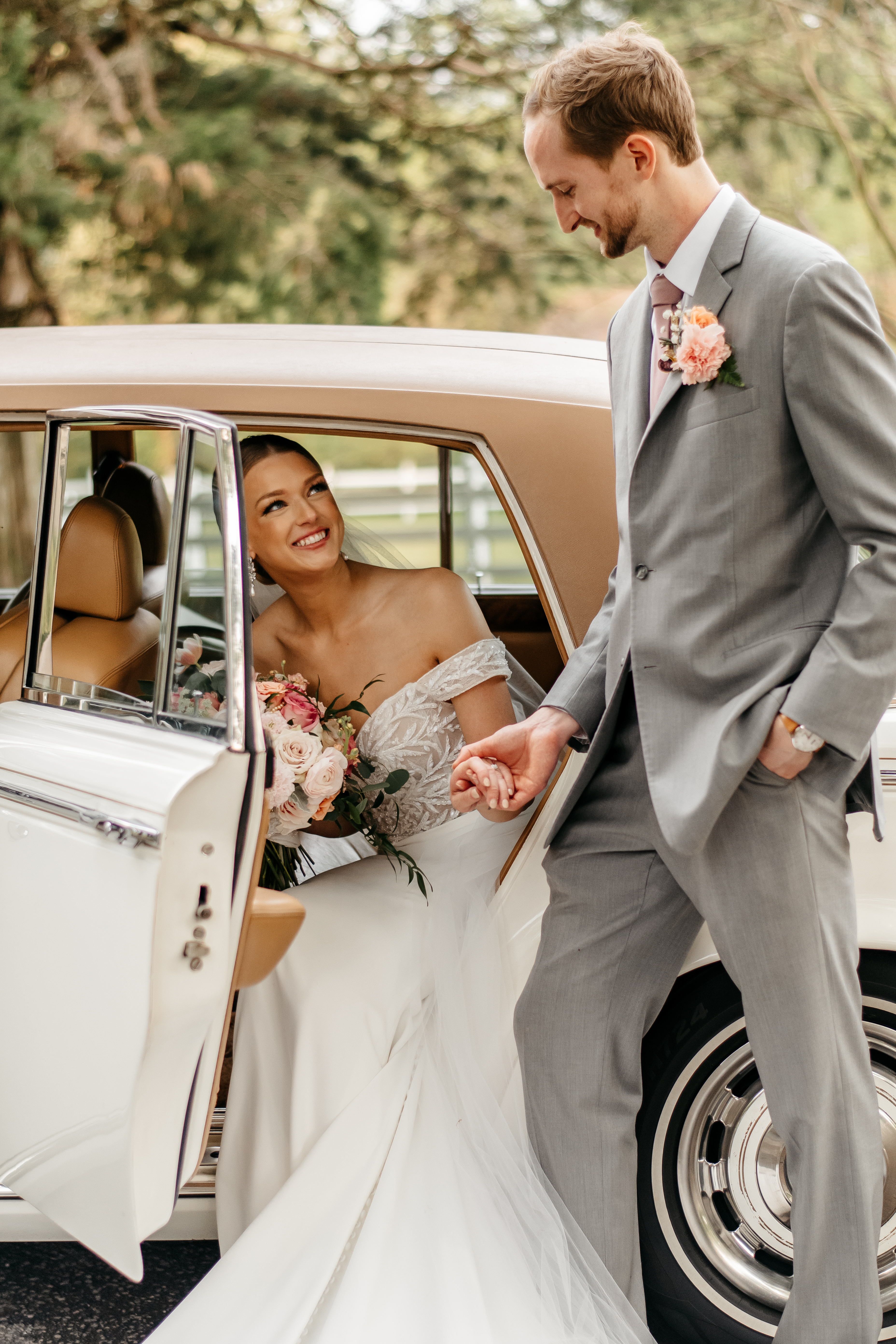 Bride stepping out of a vintage car while holding hands with her groom at one of the best Georgia wedding venues.